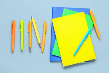 Gri arkaplanda renkli kalemleri olan defterler