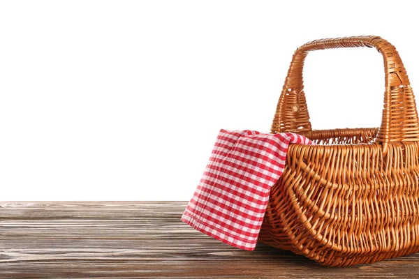 白色背景的木制桌子上有餐巾的柳条箱野餐篮 — 图库照片