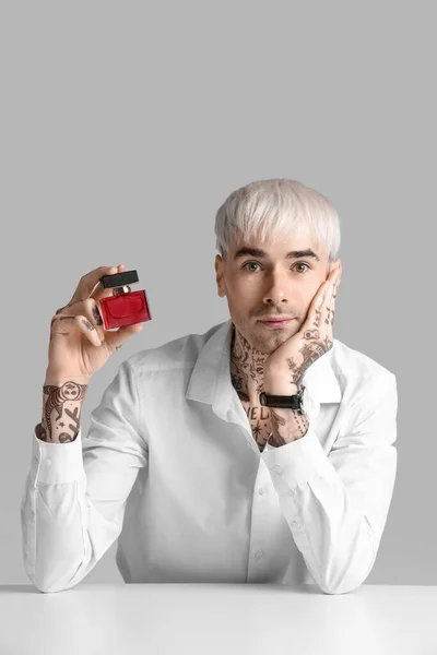 Tatuerad Ung Man Med Parfym Vid Bordet Ljus Bakgrund — Stockfoto