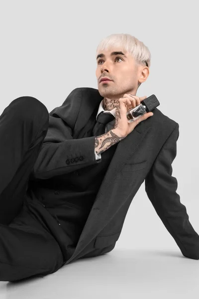 Tattooed Young Man Suit Perfume Sitting Light Background — Stock Photo, Image