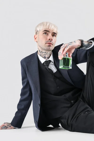 Jovem Tatuado Terno Com Perfume Sentado Fundo Claro — Fotografia de Stock