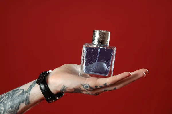 Getatoeëerde Jongeman Met Parfum Rode Achtergrond Close — Stockfoto
