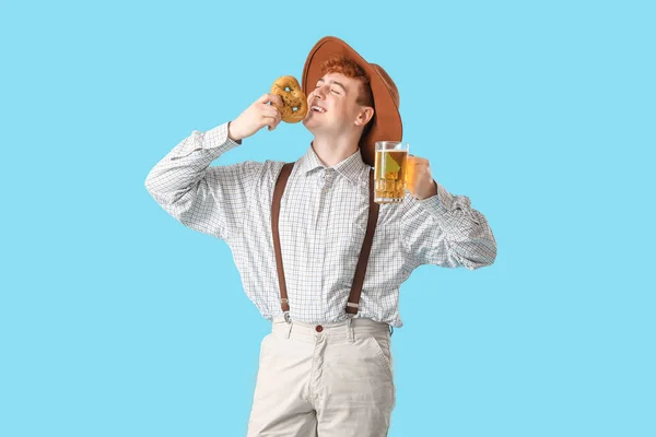 Молодой Человек Традиционной Немецкой Одежде Пивом Ест Крендель Синем Фоне — стоковое фото