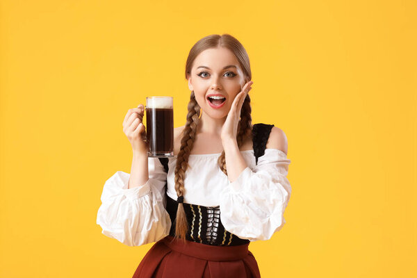 Surprised Octoberfest waitress with beer on yellow background
