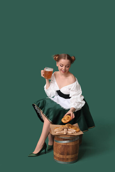 Beautiful Octoberfest waitress with beer and snacks sitting on green background