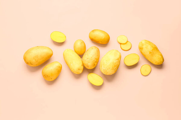 Cut and whole raw potatoes on pink background