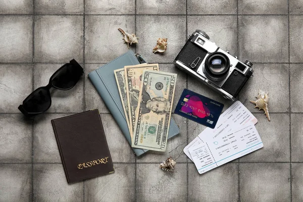 Composition with money, tickets, credit card and photo camera on grunge tile background