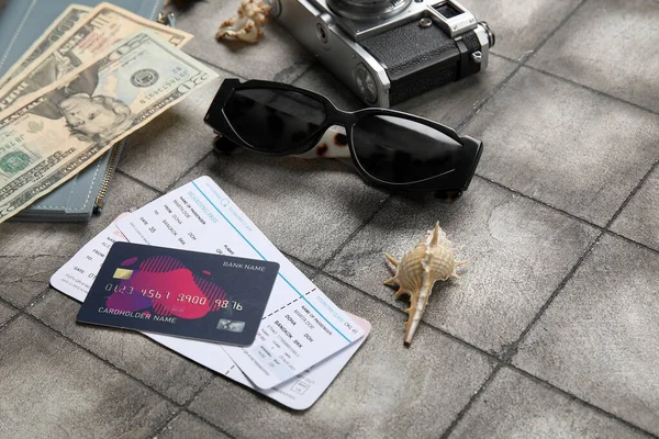 Credit card, tickets, sunglasses and money on grunge tile background