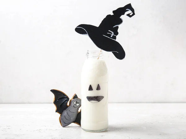 stock image Bottle of milk, hat made of paper and tasty cookie for Halloween on light background