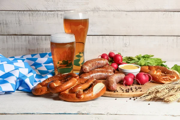 stock image Glasses of cold beer and plate with different snacks on light wooden background. Oktoberfest celebration