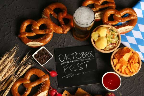 一杯冰镇啤酒 Oktoberfest 字样的黑板和黑色背景的不同小吃 — 图库照片