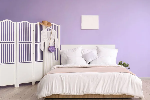 快適なベッド 白い枕と折りたたみ画面上のドレスを備えたスタイリッシュなベッドルームのインテリア — ストック写真
