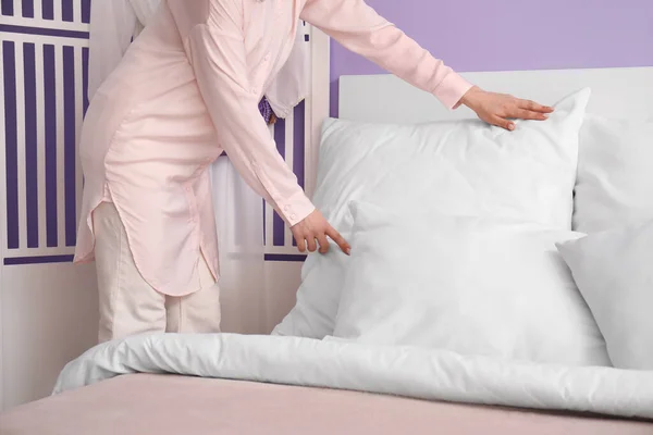 パジャマ姿の女性が家でベッドを作る — ストック写真