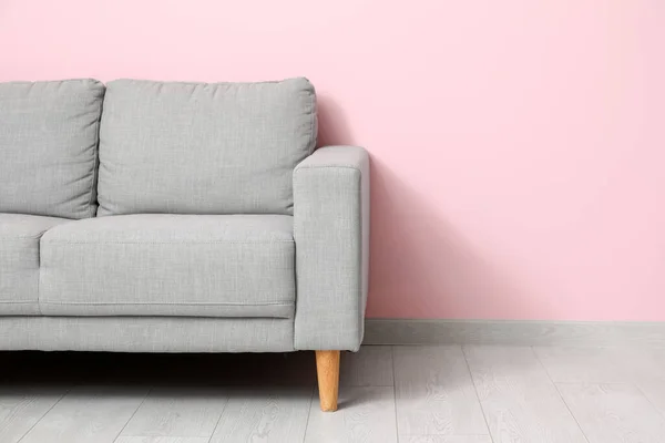 ピンクの壁の近くの居心地の良い灰色のソファ — ストック写真