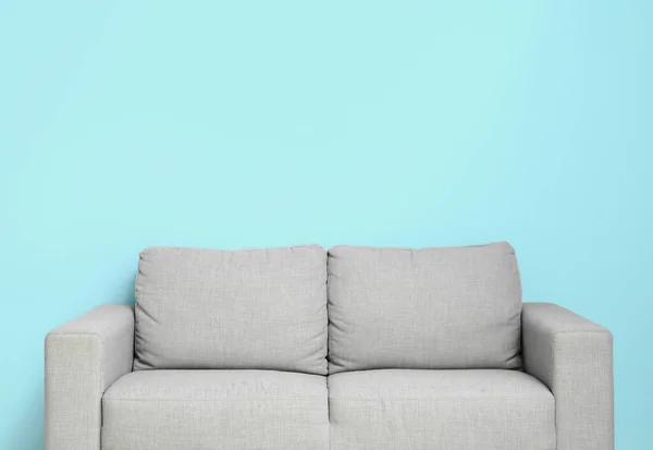 青い壁の近くの居心地の良い灰色のソファ — ストック写真