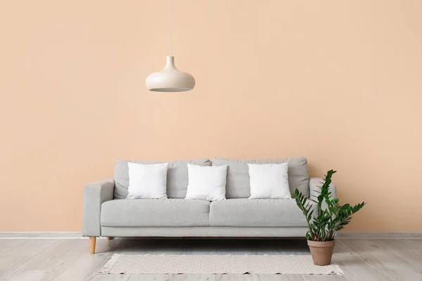 Grey sofa with white pillows near beige wall