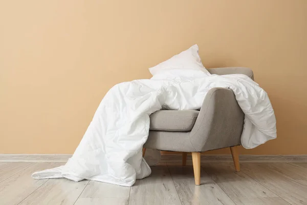 米色墙边有白色毯子和枕头的灰色扶手椅 — 图库照片
