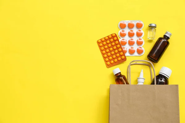 黄色の背景に異なる薬とショッピングバッグ — ストック写真