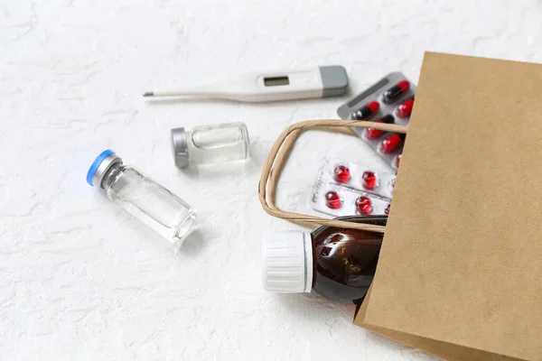 白いテクスチャの背景に異なる薬とショッピングバッグ — ストック写真