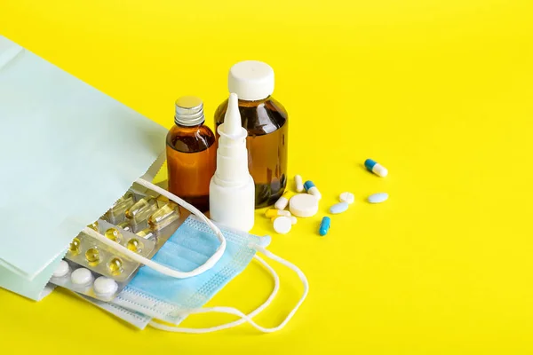 黄色の背景に異なるボトルや薬とショッピングバッグ — ストック写真