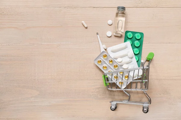 ミニショッピングカートで異なる丸薬でベージュ木製の背景 — ストック写真