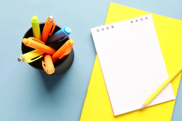 灰色の背景にカラフルなペンで空のノートとカップ — ストック写真