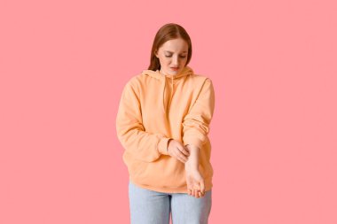 Pembe arka planda kaşınan alerjik genç kadın.