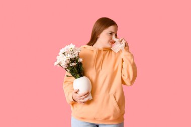 Çiçekleri ve pembe arka planda dokuları olan alerjik genç bir kadın.