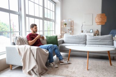 Genç adam izin gününde evde çay içiyor.