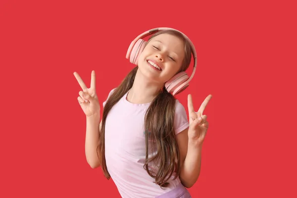 Kulaklıklı Küçük Kız Kırmızı Arka Planda Dans Ediyor — Stok fotoğraf