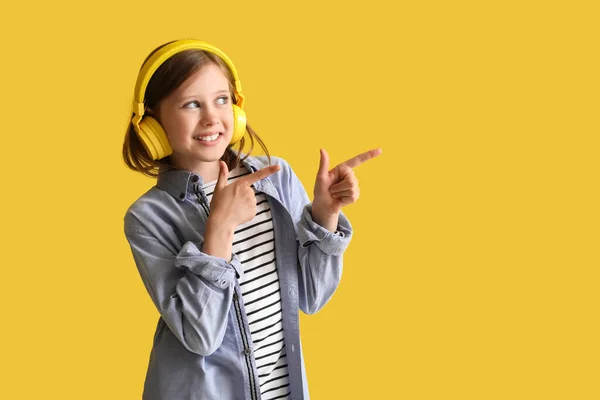 Κοριτσάκι Ακουστικά Που Δείχνει Κάτι Κίτρινο Φόντο — Φωτογραφία Αρχείου
