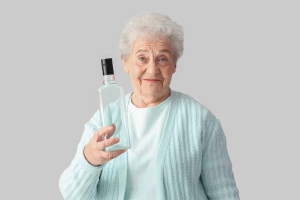 Seniorin Mit Flasche Wodka Auf Hellem Hintergrund — Stockfoto