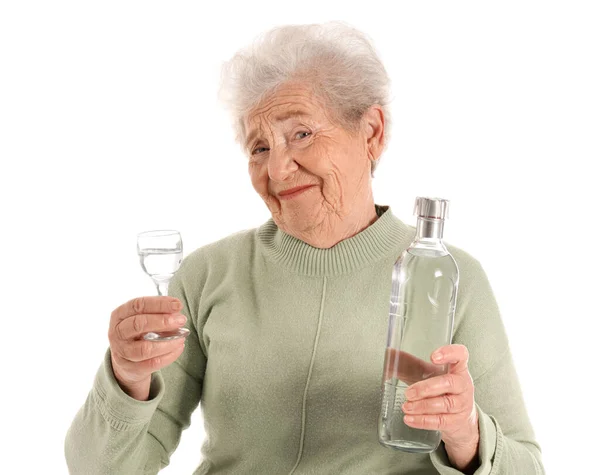 stock image Senior woman with glass and bottle of vodka on white background