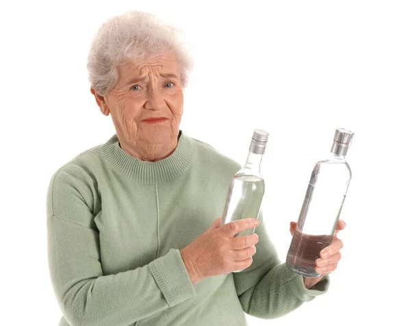 Недовольная Пожилая Женщина Бутылками Водки Белом Фоне — стоковое фото