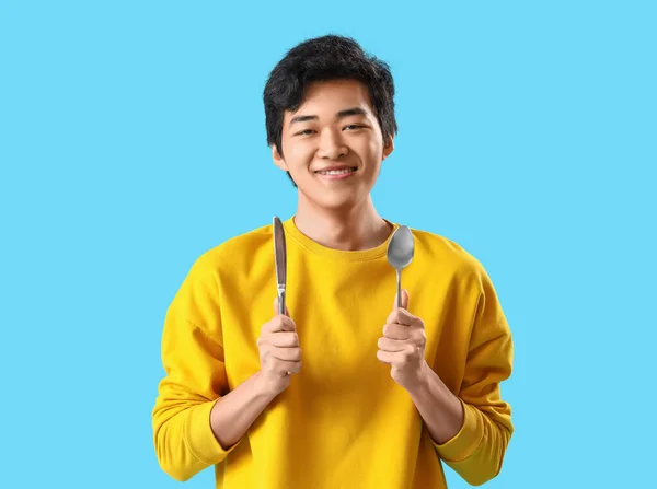 Mladý Asijský Muž Nožem Lžičkou Modrém Pozadí — Stock fotografie