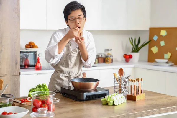 Genç Asyalı Adam Mutfakta Yemek Tadıyor — Stok fotoğraf