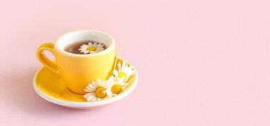 Pembe arka planda bir fincan doğal papatya çayı.