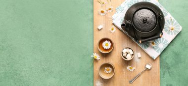 Yeşil grunge arkaplan üzerinde doğal papatya çayı ile çaydanlık.