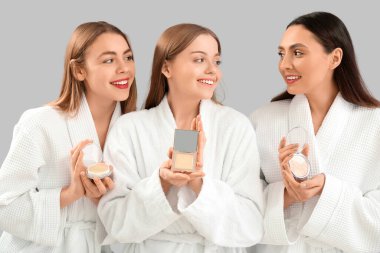 Gri arkaplanda makyaj tozu olan genç kadınlar