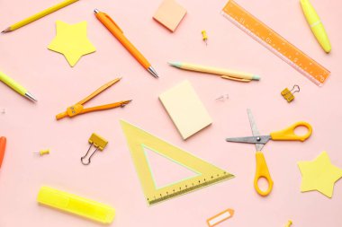 Pembe arka planda kırtasiye malzemeleriyle kompozisyon
