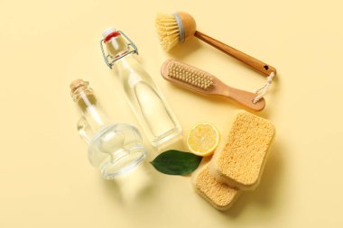 Renkli arka planda sirke, fırça, sünger ve limon şişeleri