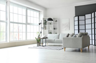 Işıl ışıl oturma odasının içinde rahat gri kanepe ve sehpanın üzerinde modern dizüstü bilgisayar.