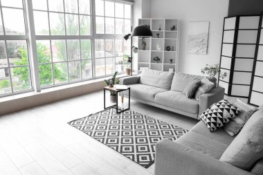 Işıl ışıl oturma odasının içinde rahat gri kanepe ve sehpanın üzerinde modern dizüstü bilgisayar.