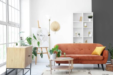 Büyük pencerenin yanında kahverengi kanepe ve kahve masası olan aydınlık oturma odasının içinde.