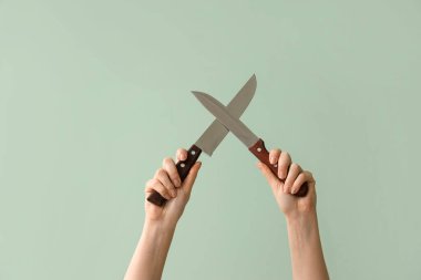 Yeşil arka planda mutfak bıçakları olan kadın.