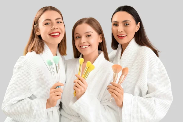 stock image Young women with makeup brushes on grey background