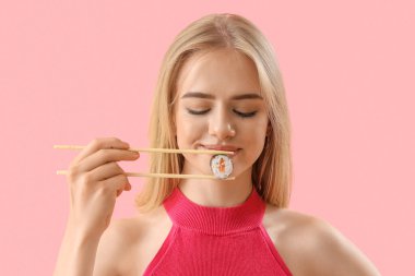 Pembe arka planda lezzetli suşisi olan genç bir kadın, yakın plan.