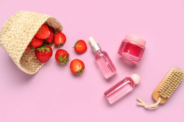Renkli arkaplanda çilek, kozmetik ürünler ve masaj fırçası kompozisyonu