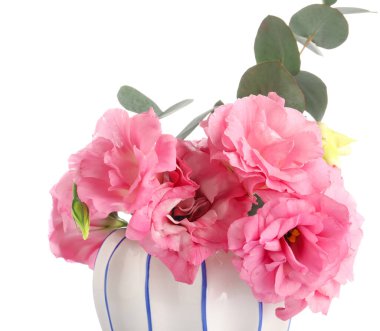 Beyaz arka planda pembe Eustoma çiçekleri olan vazo.