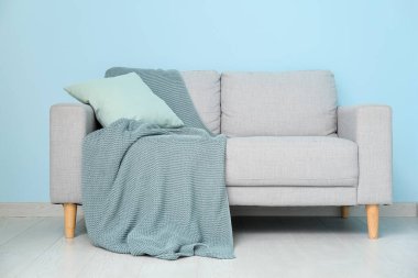 Mavi duvarın yanında kanepesi olan oturma odasının içinde.